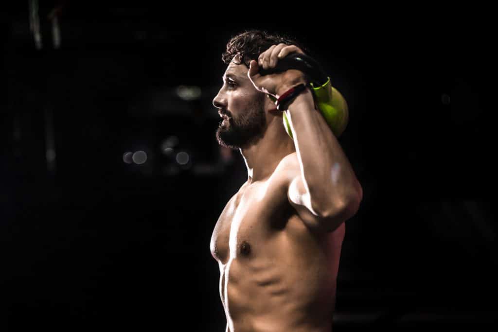 Izmos férfi kettlebell edzés közben – a szteroid használat hatása az izomnövekedésre.
